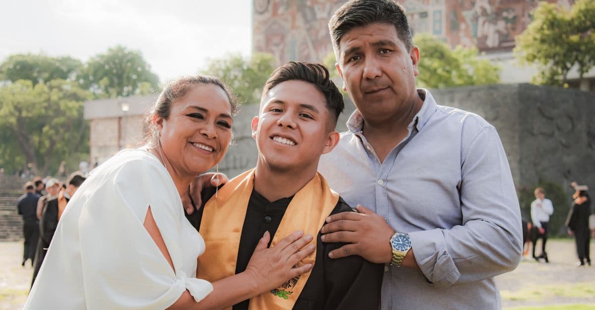 Parents embracing their graduate after a commencement ceremony