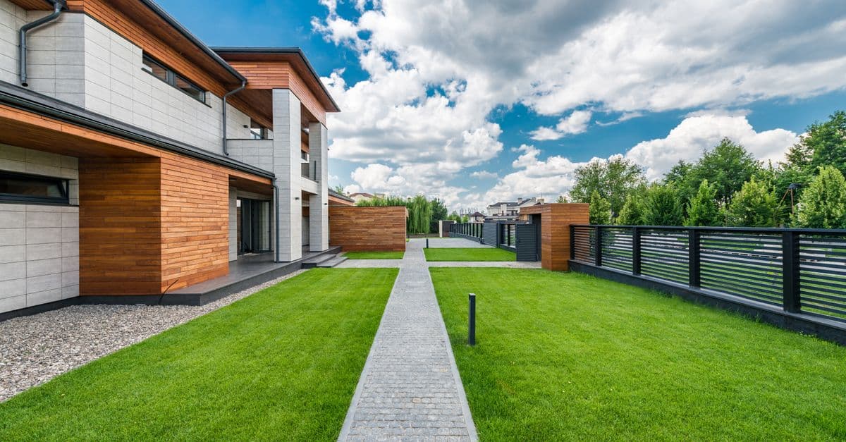 Contemporary residential home behind a green yard and trees