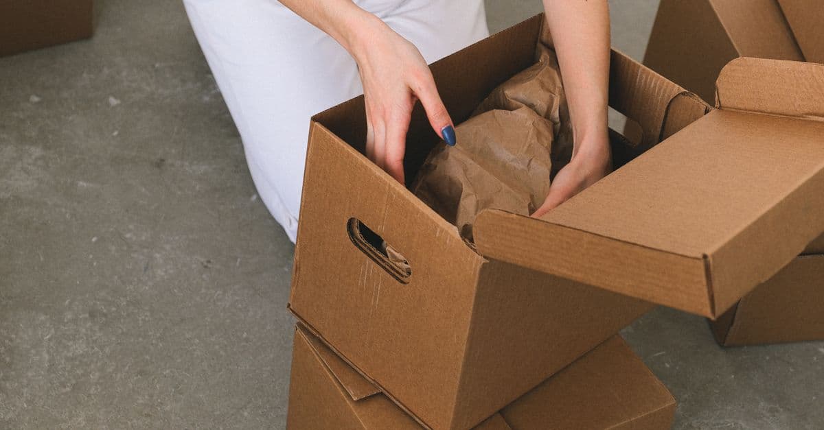 Person packing household belongings into a moving box