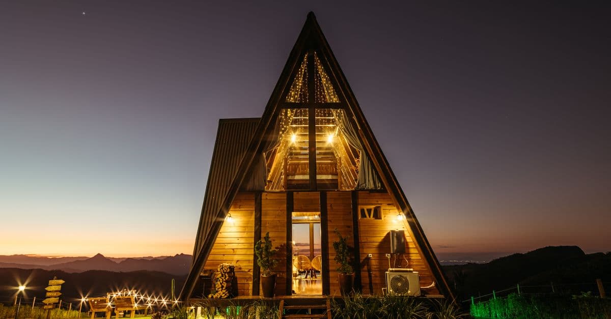 A-frame vacation rental illuminated at dusk in the mountains
