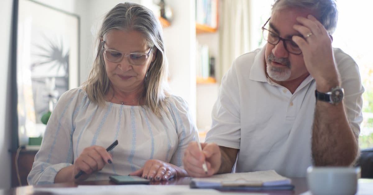 Senior couple reviewing expenses and making notes together
